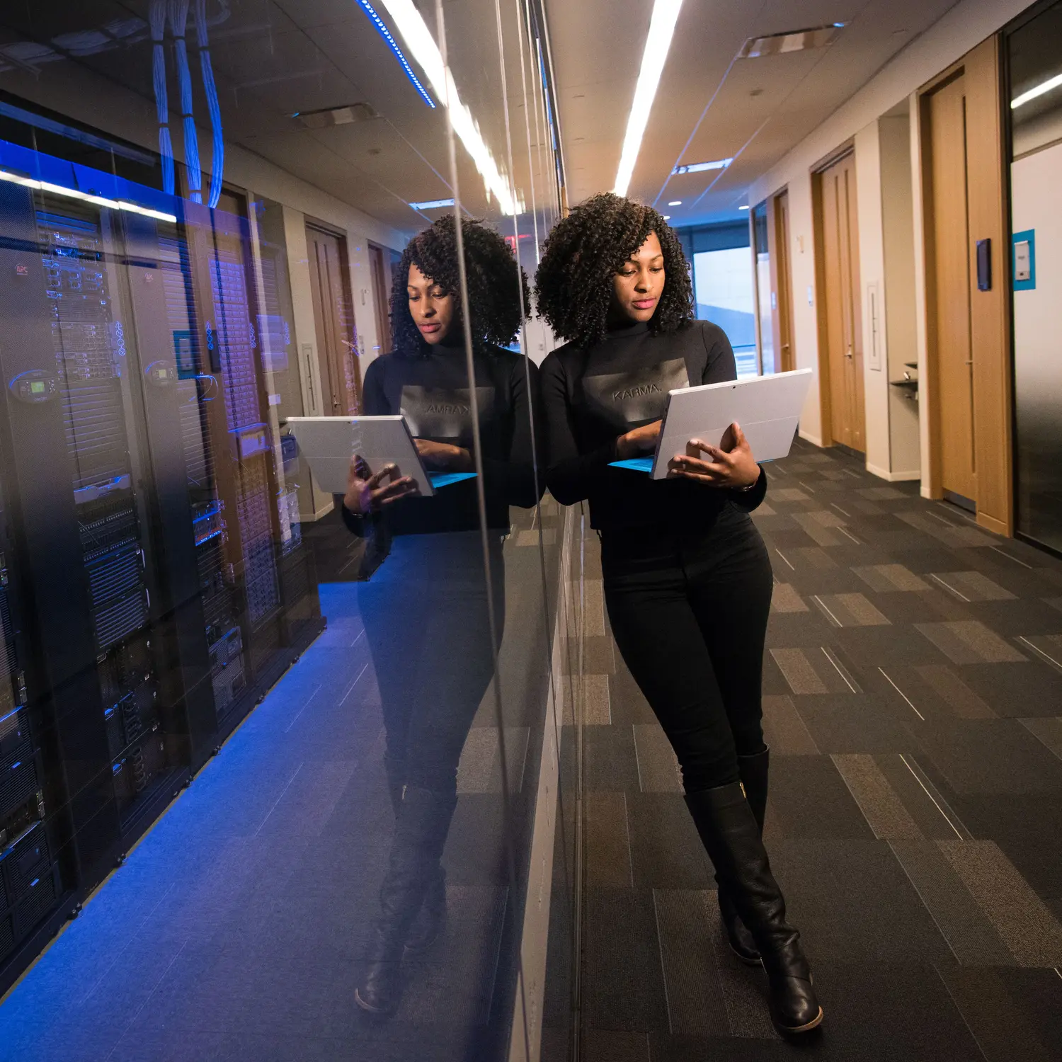 A person reviewing a laptop in a data centre corridor lined with server racks